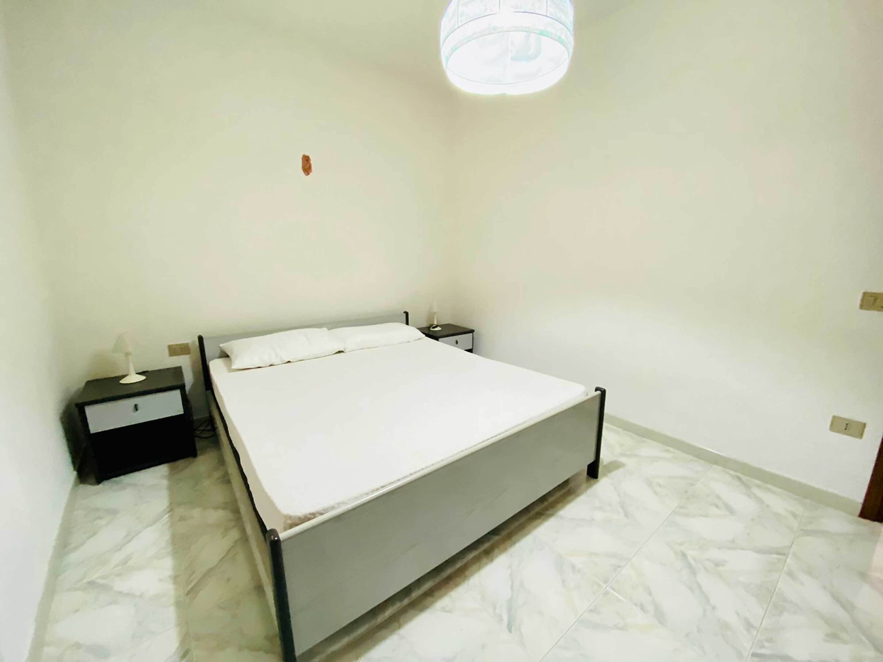 A bedroom with a bed, a nightstand, and a bedside lamp.