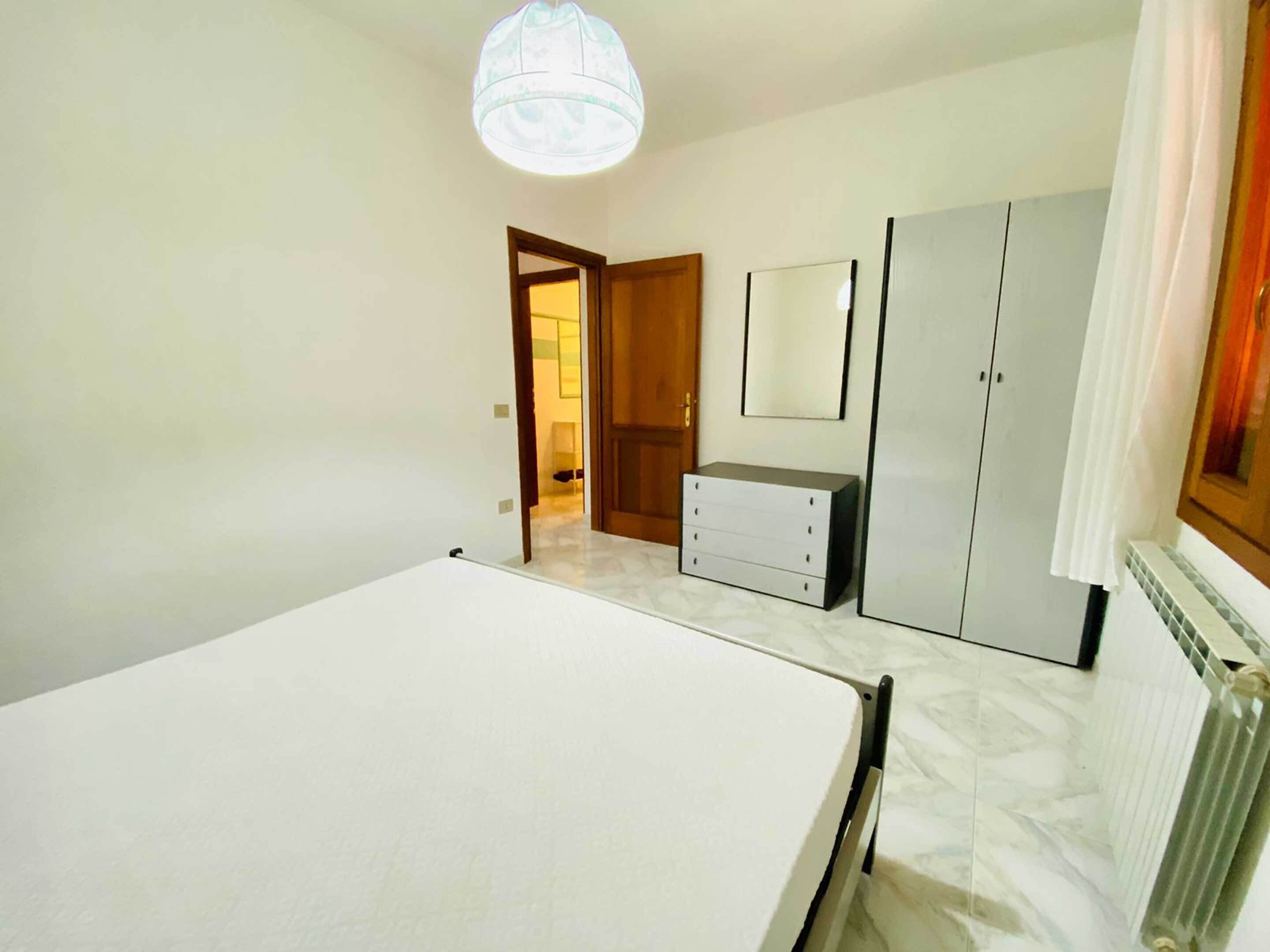 Un dormitorio con cama, cómoda, espejo y armario.