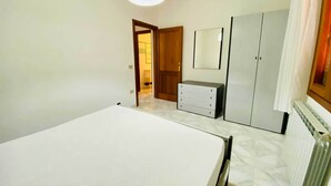 A bedroom with a bed, a dresser, a mirror, and a wardrobe. - Casa Vacanza Silvaredda (San Teodoro)