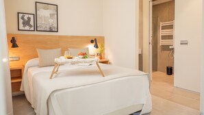 A neatly made bed with a tray of breakfast items, a bedside table with a lamp, and two framed pictures on the wall. - U-Sense Sevilla Catedral (Seville)