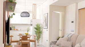 A modern living room with a beige sofa, a wooden coffee table, and a dining area with a table and chairs. - U-Sense Sevilla Catedral (Seville)