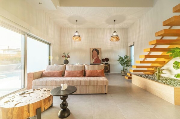 A modern living room with a sofa, coffee table, and a staircase with a plant.