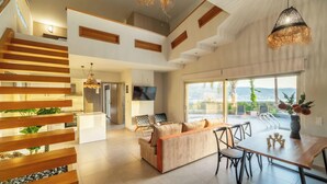 A spacious living area with a modern staircase, a dining table, and a sofa. - Villa Jarko (Chania)
