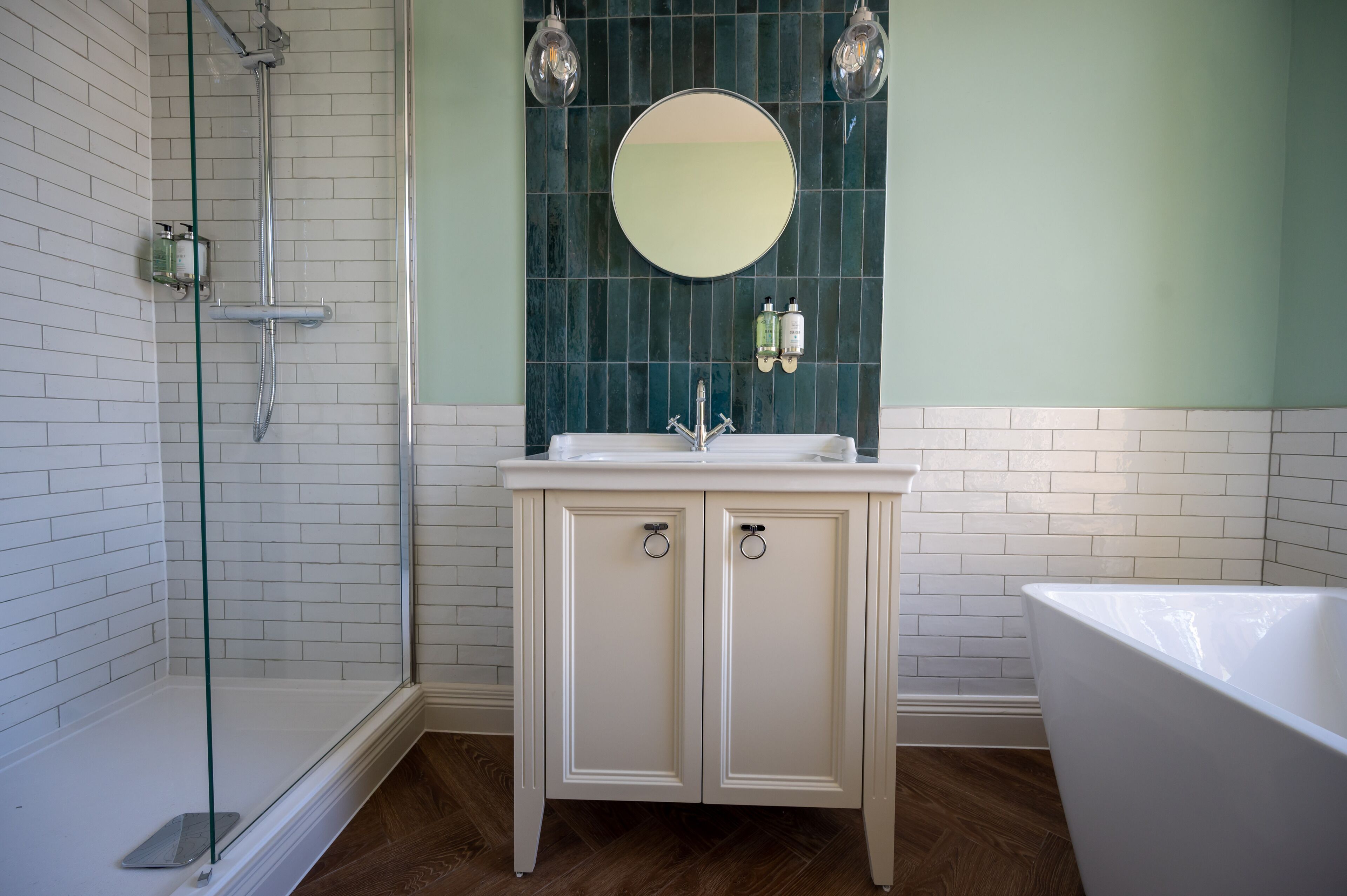 A bathroom with a glass shower enclosure, a white sink with a mirror above it, and a bathtub.