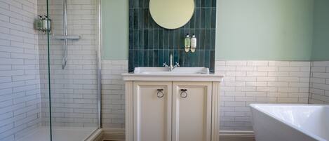 A bathroom with a glass shower enclosure, a white sink with a mirror above it, and a bathtub.