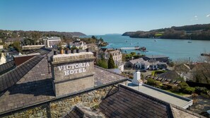 A Victorian Hotel with stone architecture, located near a body of water with boats and a pier. - Victoria Hotel Menai Bridge By Chef and Brewer Collection (Menai Bridge)