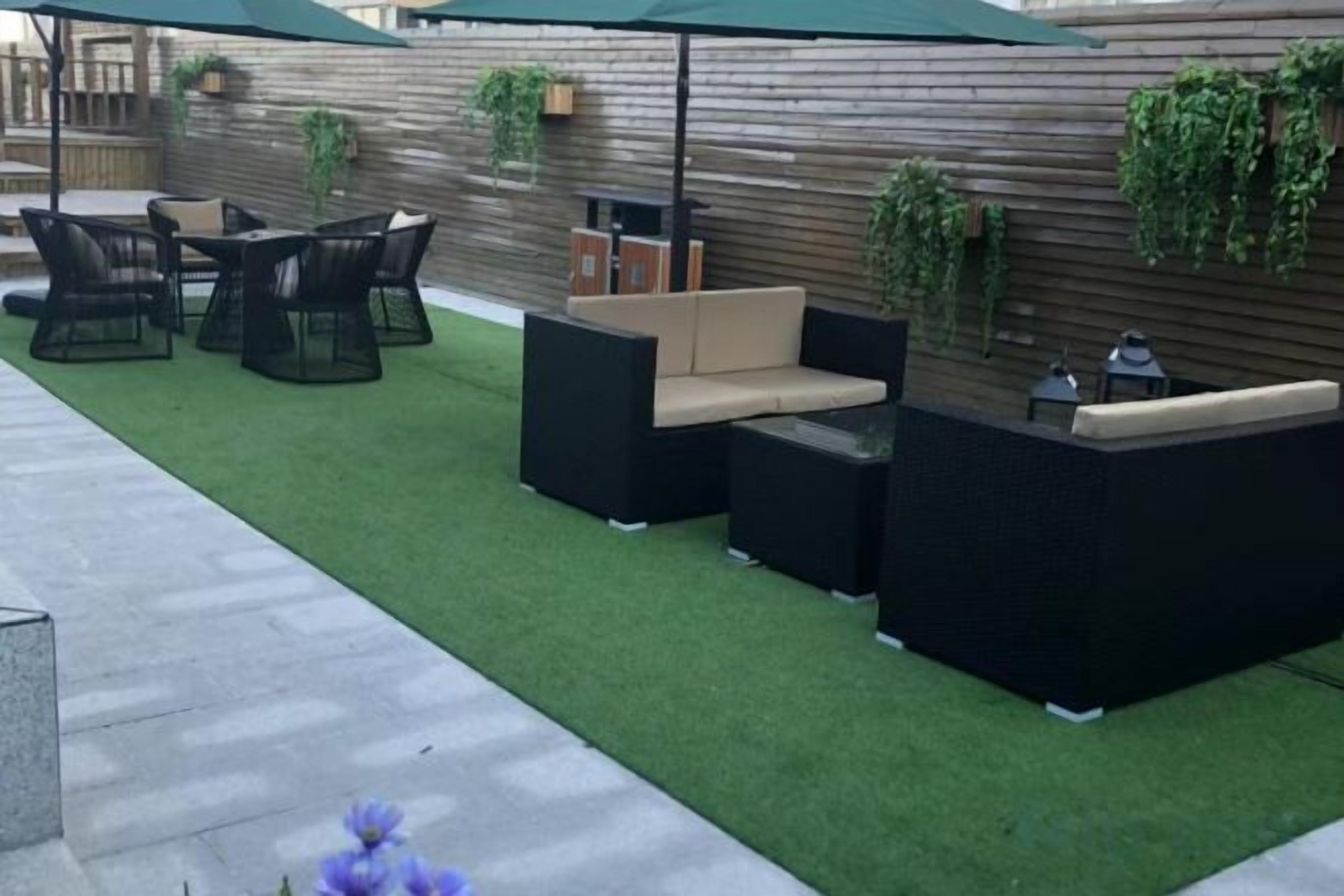 An outdoor patio with a sectional sofa, a dining table with chairs, and a small table with a lamp.