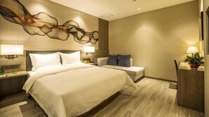 Een moderne hotelkamer met een groot bed, een nachtkastje, een stoel, een bureau en een wanddecoratie.