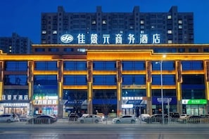 Een hotel met een moderne gevel, meerdere verdiepingen en een parkeerplaats ervoor.