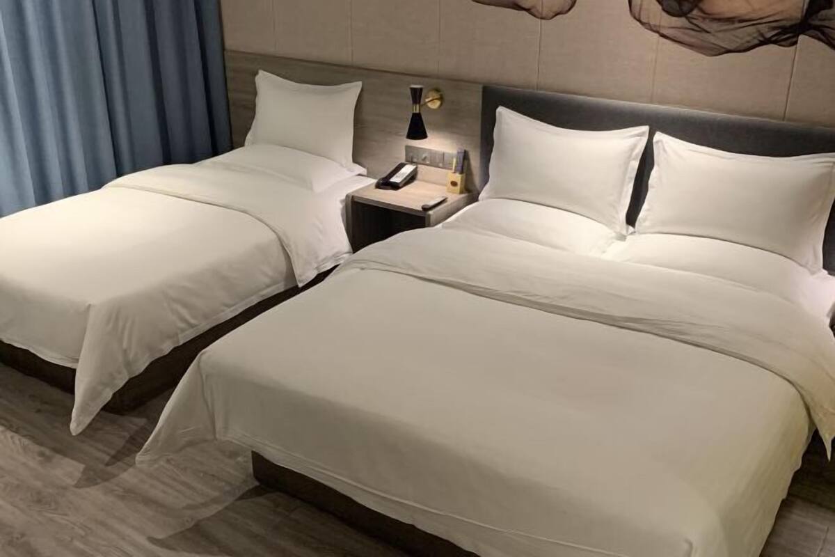 Une chambre d’hôtel avec deux lits simples, chacun doté d’une table de chevet, d’une lampe et d’un téléphone.