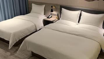 A hotel room with two single beds, each with a nightstand, a lamp, and a phone.