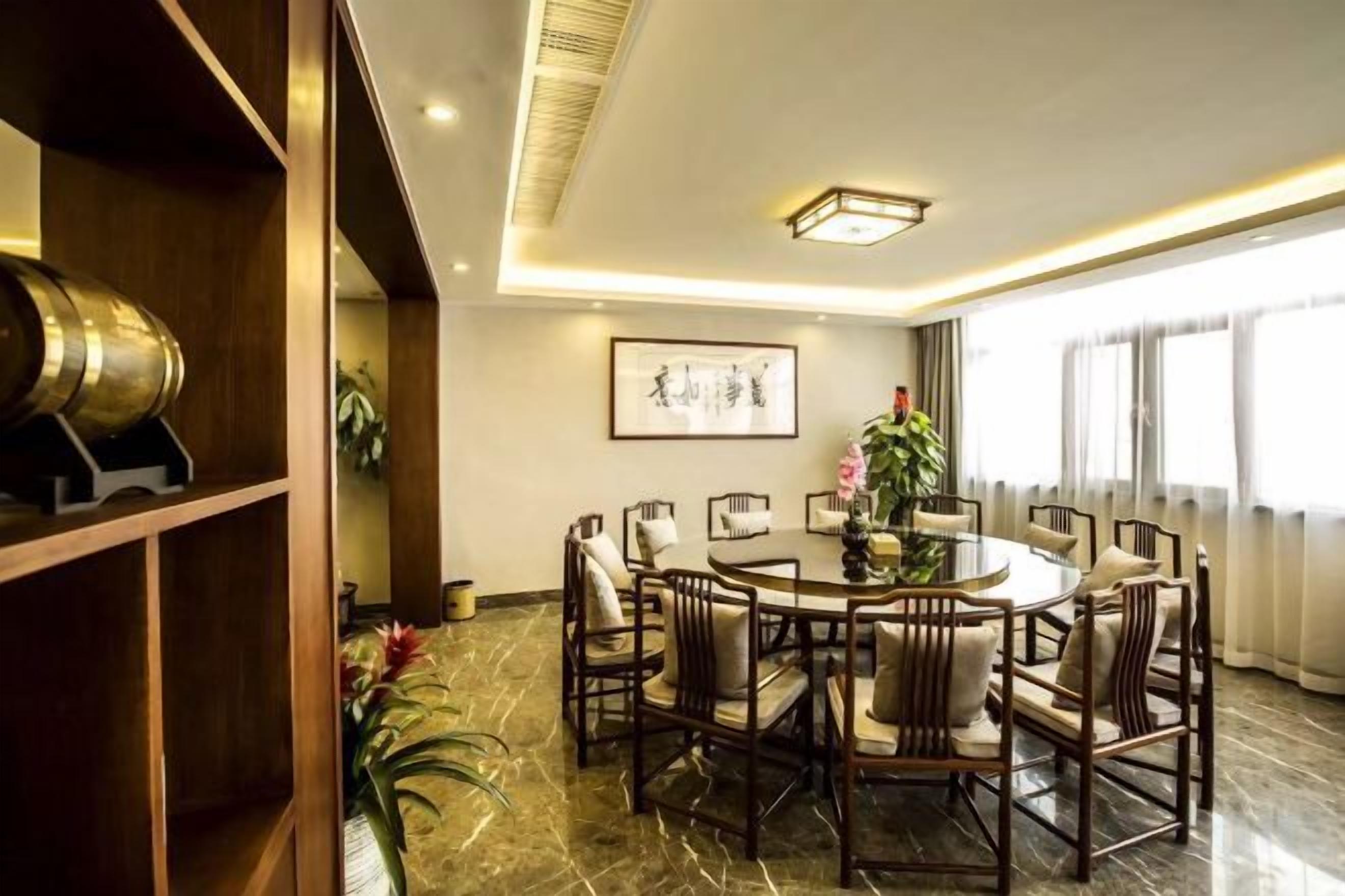 A dining area with a round table, multiple chairs, and a wooden bookshelf.