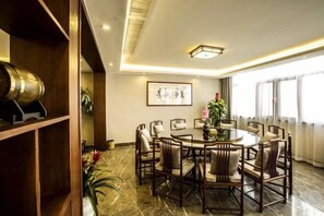 Un comedor con una mesa redonda, varias sillas y una estantería de madera.