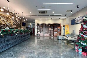 Un vestíbulo con mostrador de recepción, un árbol de Navidad y una exhibición de regalos.