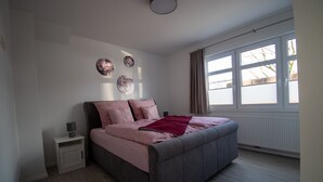A bedroom with a bed, nightstand, and window.
