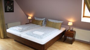 A double bed with a wooden frame, two bedside tables with lamps, and a radiator. - Haus Fischernetz (Leezdorf)