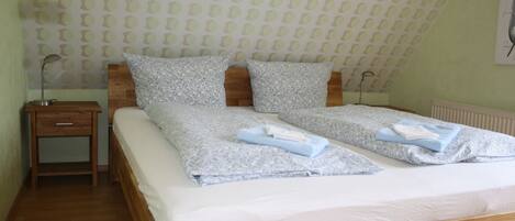 A bedroom with a wooden bed, patterned pillows, a nightstand, and a wall with a circular pattern.