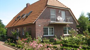 A two-story brick house with a sloped roof, a balcony with a metal railing, and a number '68' on the front wall. - Haus Fischernetz (Leezdorf)
