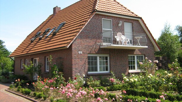A two-story brick house with a sloped roof, a balcony with a metal railing, and a number '68' on the front wall. - Haus Fischernetz (Leezdorf)