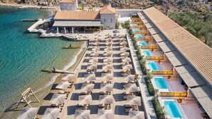 Eine Vogelperspektive zeigt ein Resort mit Strand, mehreren Schwimmbecken und Liegestühlen.