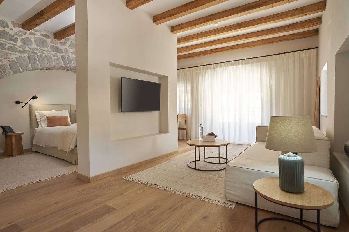 Ein modernes Schlafzimmer mit einem Bett, einem Fernseher, einer Couch und einer Lampe.