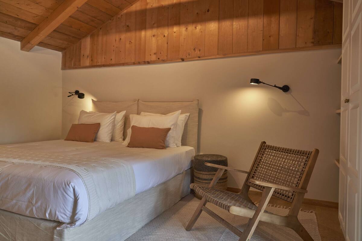 Ein Schlafzimmer mit einem Bett, einem Sessel und einer Lampe.