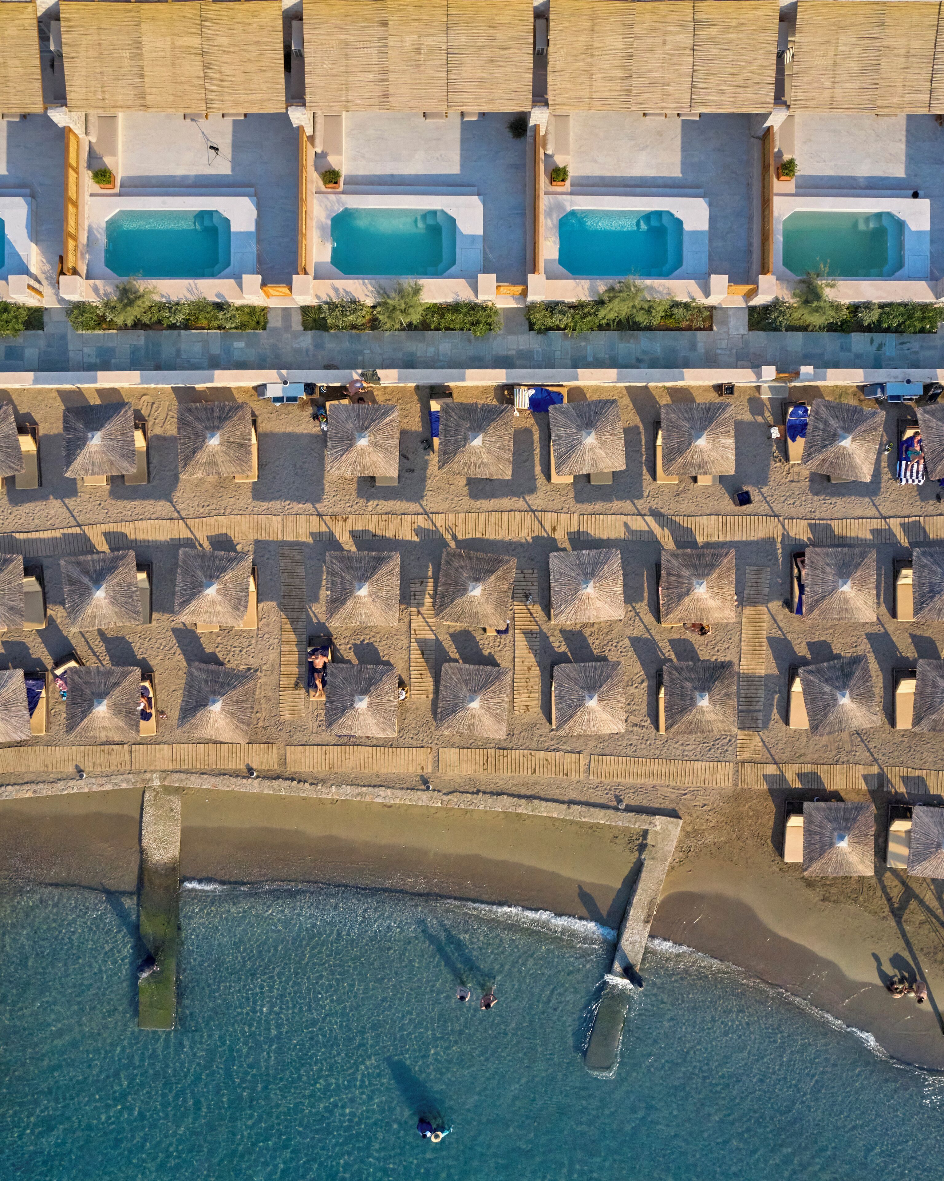 An aerial view of a beach resort with multiple swimming pools, sun loungers, and umbrellas.