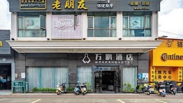 A hotel with a signboard for Wanpeng Hotel and another sign for a nearby business.