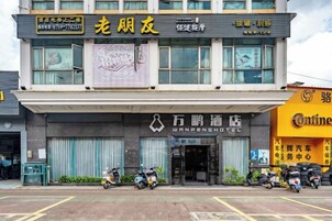 Un hotel con un letrero que indica Wanpeng Hotel y otro anuncio para un negocio cercano.