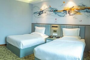 Een hotelkamer met twee bedden, een muurschildering en een kamerbreed tapijt met dessin.