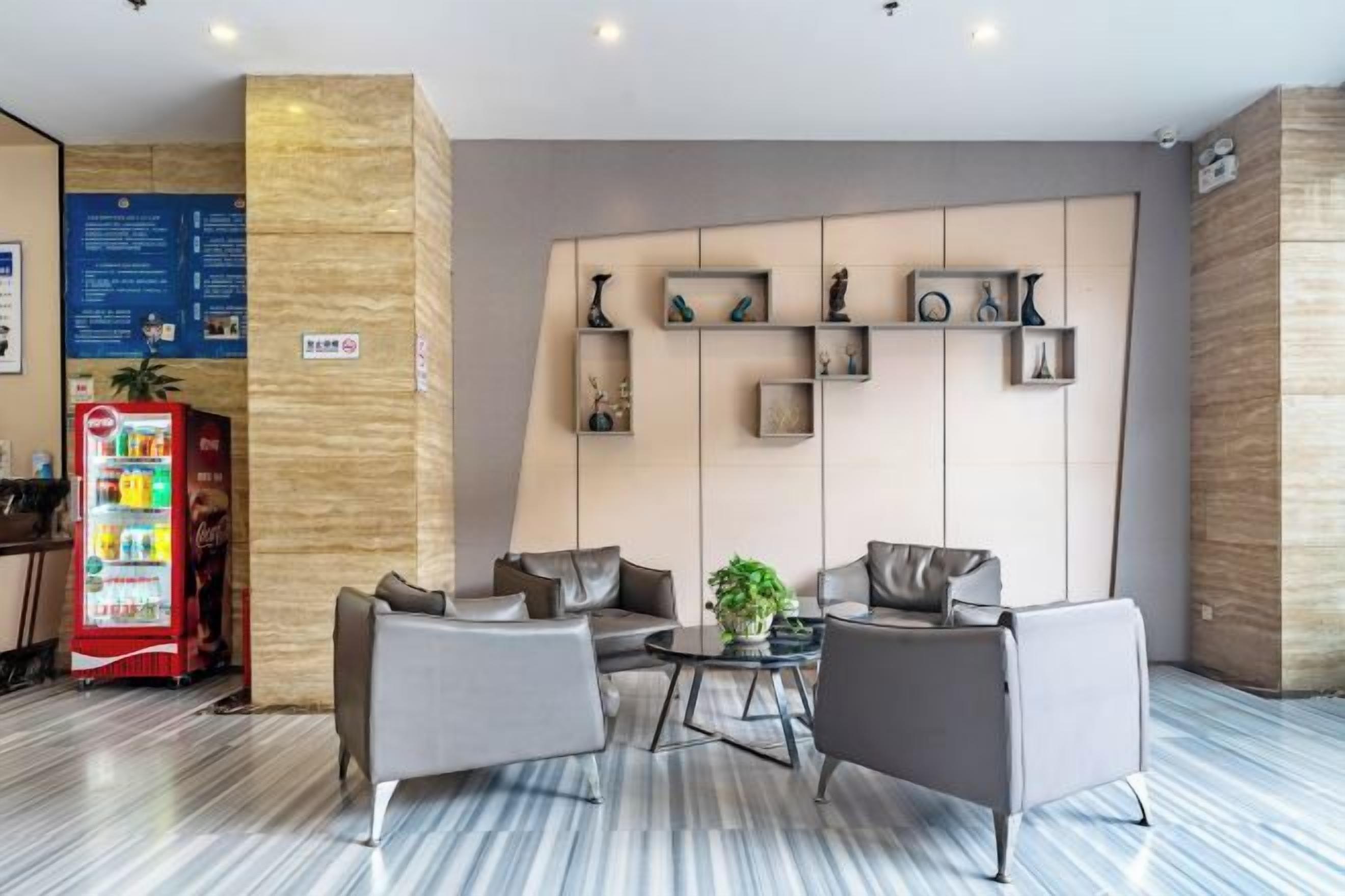 A hotel lobby with seating, a vending machine, and a wall with shelves.