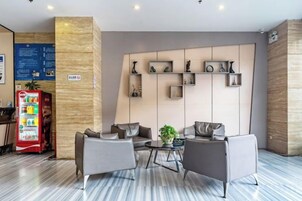 Un hall de hotel con asientos, una máquina expendedora y una pared con estanterías.