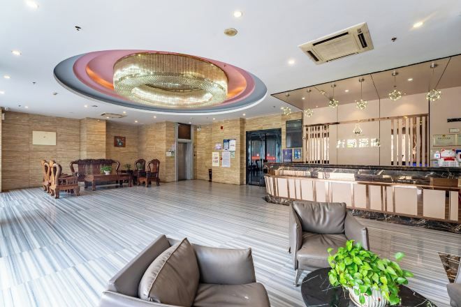 A spacious lobby with a reception desk, seating area, and a modern chandelier.