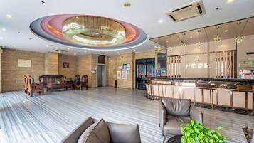 A spacious lobby with a reception desk, seating area, and a modern chandelier.