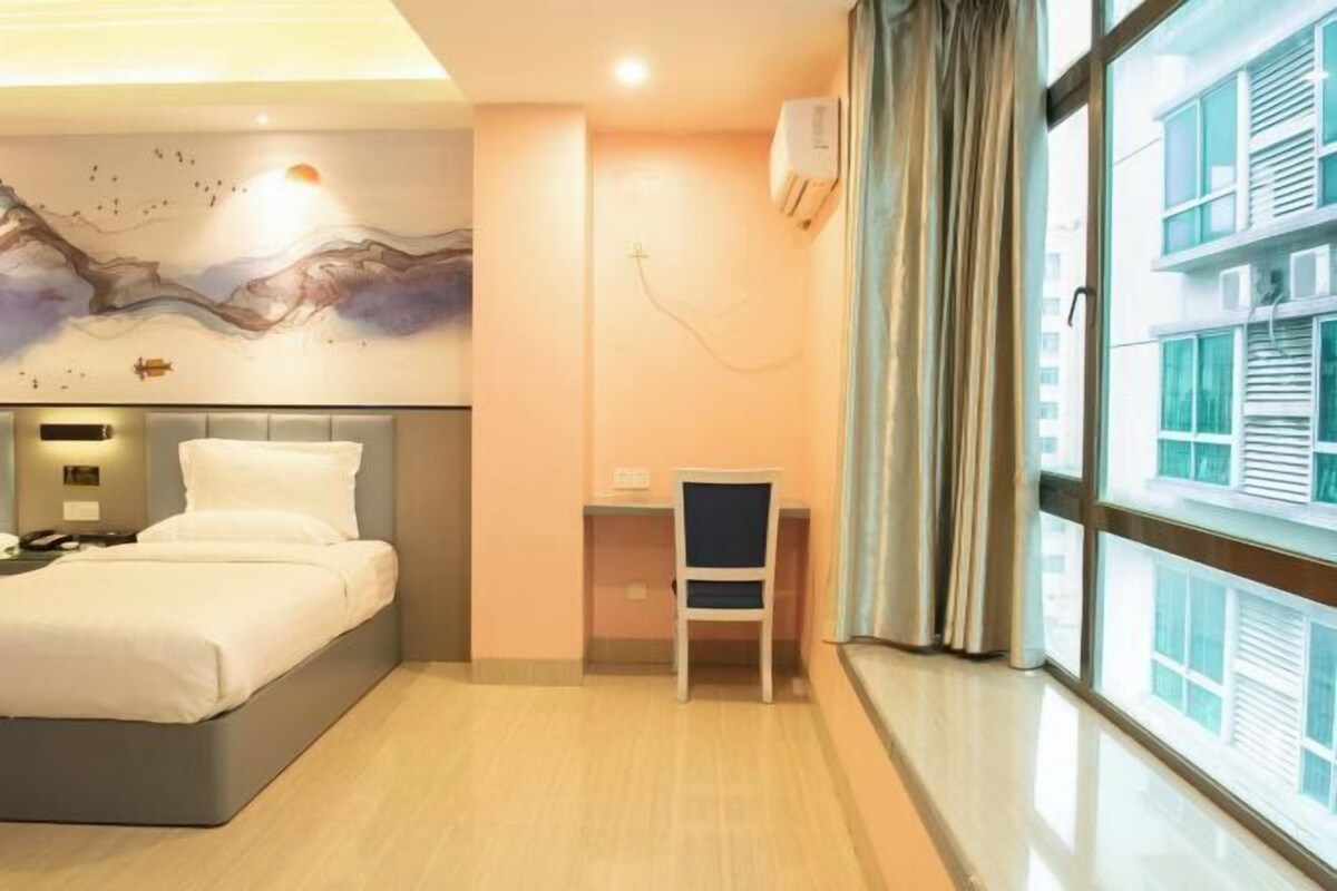Een hotelkamer met een bed, een bureau en een groot raam met gordijnen.