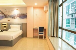 Una habitación de hotel con una cama, un escritorio y un ventanal con cortinas.