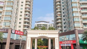 A multi-story residential building with balconies, a central archway, and various commercial establishments on the ground floor. - Wanpeng Hotel (Zhanjiang Suixi Quanfeng Plaza Branch) (Suixi)