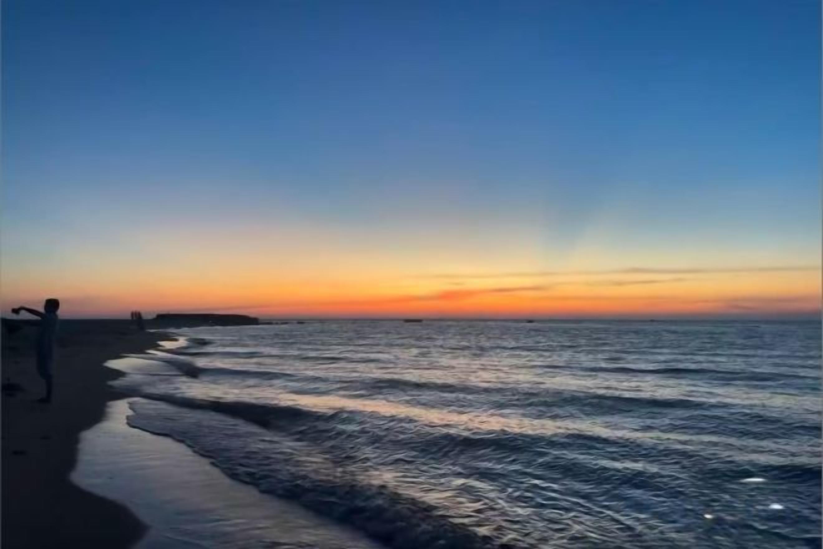 En strand med klar himmel och stilla hav.