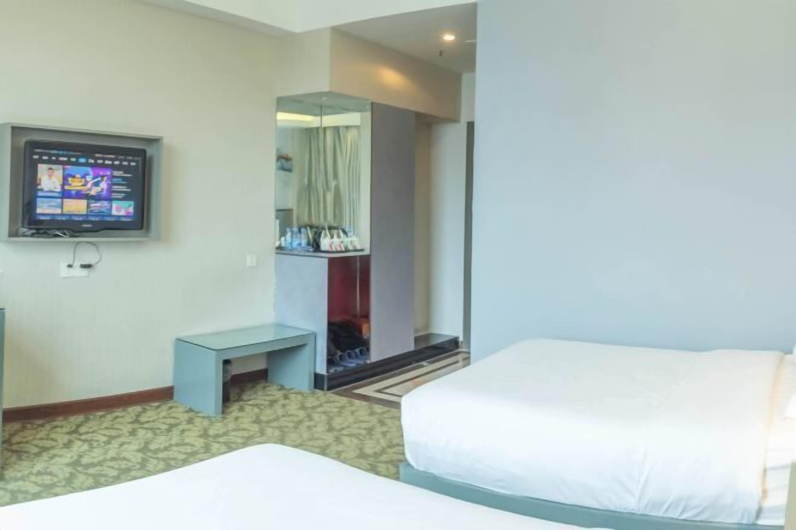 A hotel room with two beds, a television, a small table, and a wardrobe.