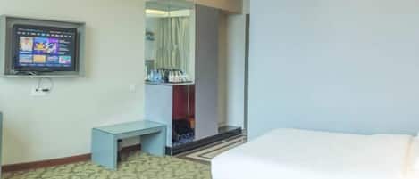 A hotel room with two beds, a television, a small table, and a wardrobe.