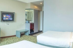 Een hotelkamer met twee bedden, een televisie, een kleintje tafel en een garderobe.
