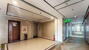 A hotel corridor with a marble floor, wooden doors, and a fire extinguisher. - Wanpeng Hotel (Zhanjiang Suixi Quanfeng Plaza Branch) (Suixi)