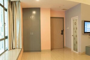 A hotel room with a large wardrobe, a door with frosted glass panels, and a television mounted on the wall. - Wanpeng Hotel (Zhanjiang Suixi Quanfeng Plaza Branch) (Suixi)