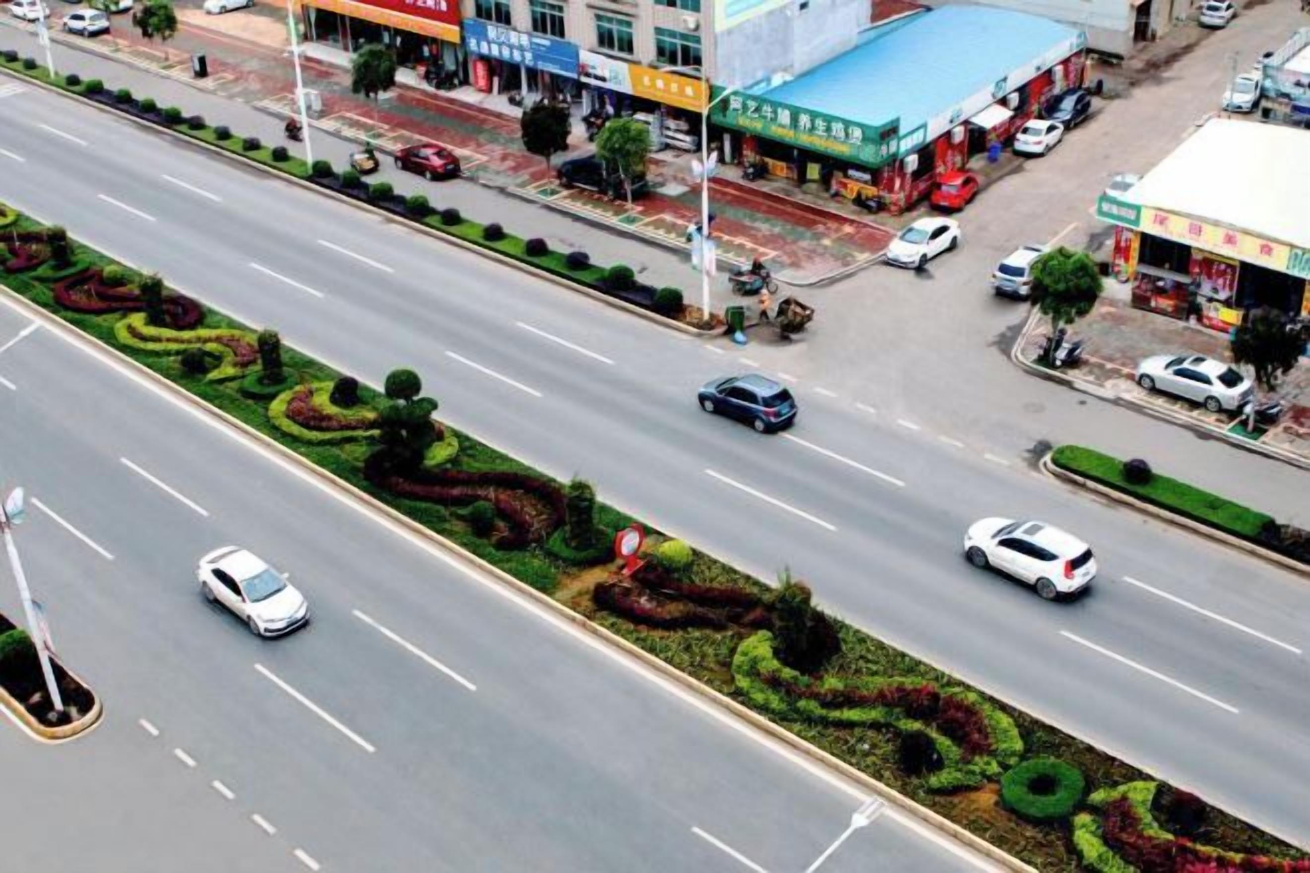A multi-lane road with vehicles, a gas station, and commercial buildings.