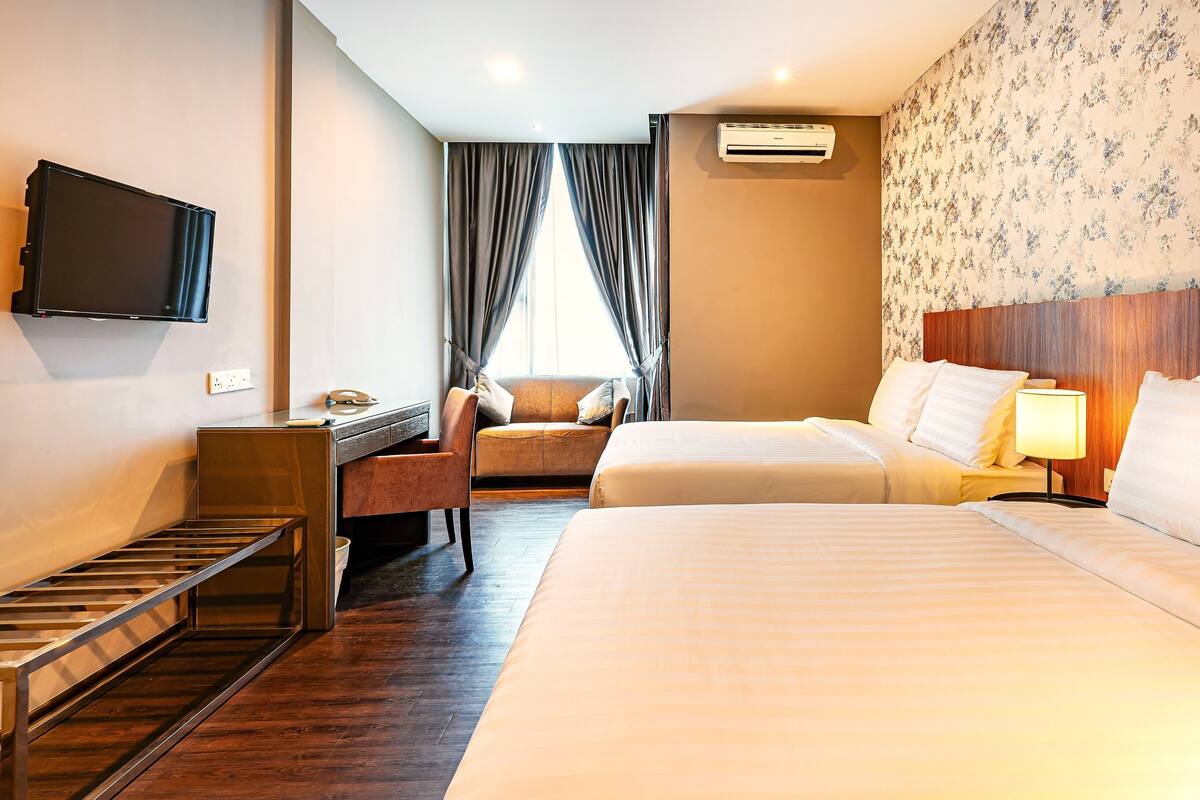 Hotellihuone, jossa on sänky, työpöytä, tuoli, televisio ja ilmastointilaite.