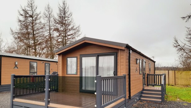 Ein eingeschossiges Holz-Mobilheim mit einer Veranda und einer Schiebetür.