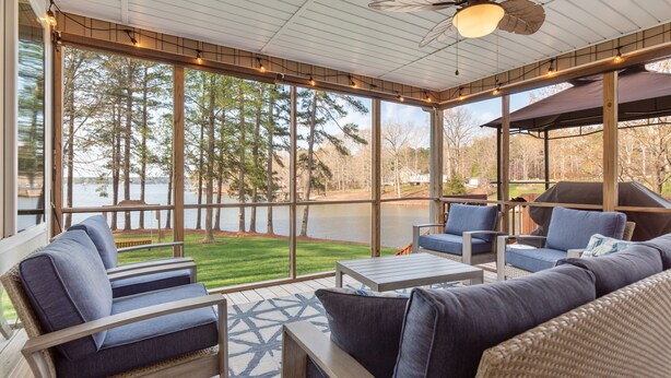 A covered outdoor seating area with a view of a lake and trees. - Dog Friendly, 370+ ft of Waterfront, dock access and kayaks! (Littleton)