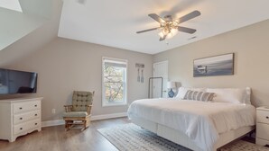 A bedroom with a bed, a television, a chair, a ceiling fan, a window, and a painting on the wall. - Dog Friendly, 370+ ft of Waterfront, dock access and kayaks! (Littleton)