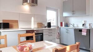 A modern kitchen with white cabinets, a black coffee maker, and a glass coffee pot. - Chic & bright apartment in Mülheim an der Ruhr (Mülheim an der Ruhr)