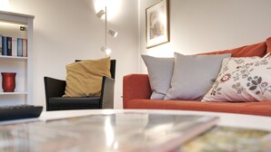 A living room with a sofa, a chair, a bookshelf, and a lamp. - Chic & bright apartment in Mülheim an der Ruhr (Mülheim an der Ruhr)